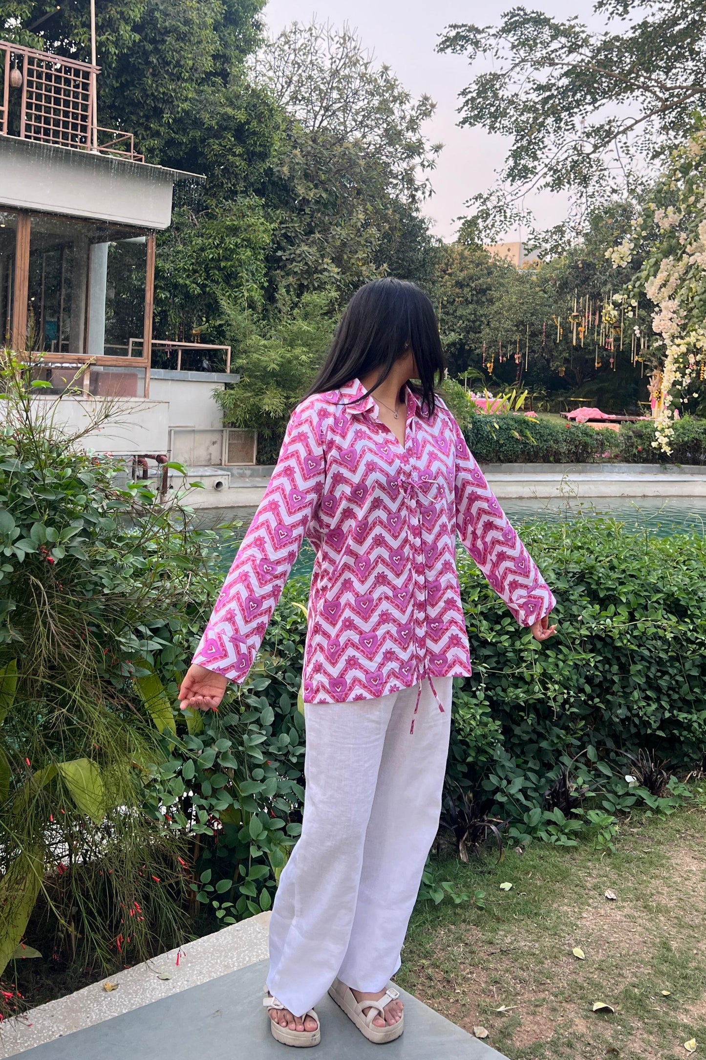 Person wearing a pink and white outfit with a zigzag pattern in an outdoor setting.